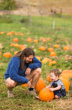 Mother and young baby playing in pumpkin patch