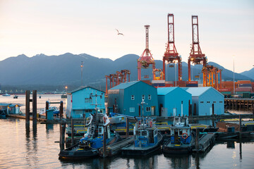 Tugboats and a shipping yard in front of mountains.