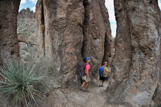 Man and woman backpackers explore the rock formations at Fremont Saddle on the popular Peralta Trail in the Superstition Wilderness Area, Tonto National Forest near Phoenix, Arizon