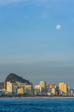 Full moon rising in sky above buildings