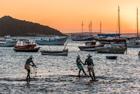 Fisherman statue in Atlantic Ocean with boats on background during sunset in Buzios, Rio de Janeiro, Brazil