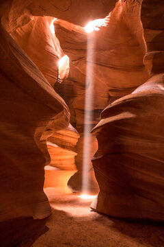 Light beam shining into orange sandstone slot canyon
