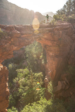 Female hiker running at sunrise across Devils Bridge in Sedona, Arizona, USA