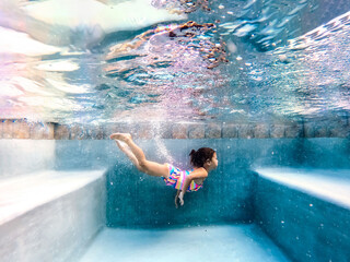 girl swimming underwater with rainbow swimsuit