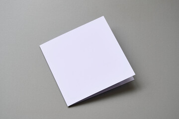 Laying blank closed empty square greeting card mock up on grey background. For use as a Christmas, birthday, wedding or celebration background template.