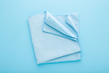 Folded dry soft microfiber rag for different surfaces wiping. Closeup. Light blue table background....