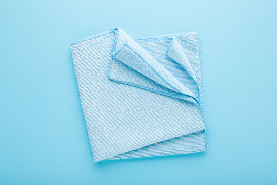Folded dry soft microfiber rag for different surfaces wiping. Closeup. Light blue table background. Pastel color. Top down view.