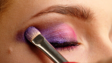 Make-up artist applies makeup to the upper eyelid, close-up.  Makeup artist applies a bright eye...
