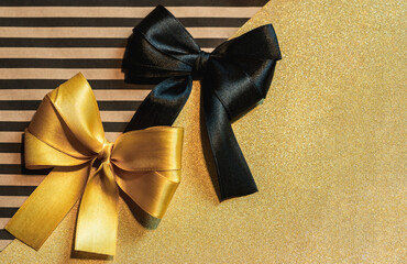 Yellow and black bows on golden and striped craft wrapping paper.Festive gift wrapping. Shiny packaging.