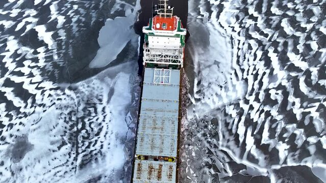 A big red ship frozen in the endless sea of ice. Aerial View of dead frozen harbour Extreme cold weather. Nature landscape famous for being heavily affected by global warming and Climate Change