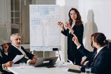 A team of businessmen at a business meeting in a conference room. The businesswoman offers her partners a new financial model of the company.