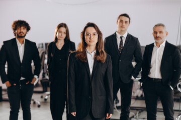 Ambitious businesswoman leading her team. Female boss standing in front of her employees. Woman business owner posing with colleagues