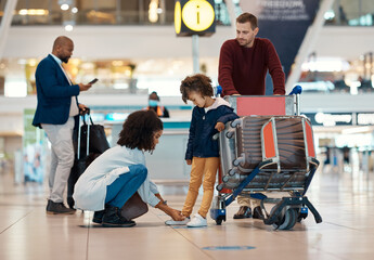 Mother tie shoes of girl at airport for travel, family holiday and vacation with luggage, suitcase and trolley. International journey, transport and mom, girl and dad waiting for flight departure