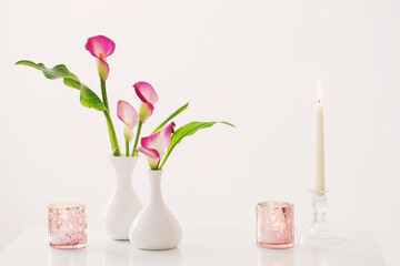 pink calla lily in vase  and burning candles on white background