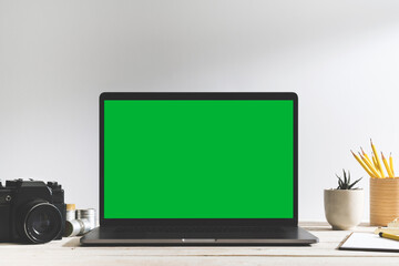 Chroma key green screen laptop on table with a film camera.