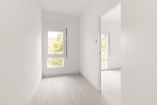 View Of An Empty White Bright Room With Window Without Furniture After Painting And Renovation With Wooden Floor And Baseboards. Concept Of Beautiful Laconic Interior For Various Inspiring Ideas