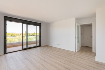 Spacious large room with wooden parquet structure and panoramic window overlooking beautiful landscape among complex of new buildings and balcony with elegant glass border. Mortgage and moving concept