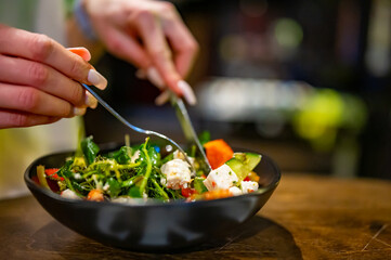 Woman's hands eat salad on table in restaurant