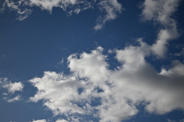 blue sky background with clouds, white rainy clouds against a blue sky illuminated by the rays of the sun white blue clouds in sunny weather against the blue sky 