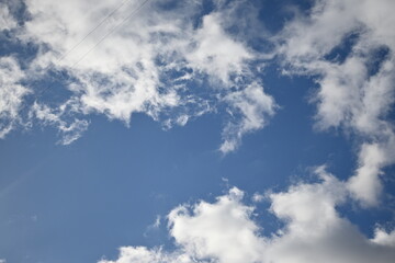 blue sky background with clouds, white rainy clouds against a blue sky illuminated by the rays of the sun white blue clouds in sunny weather against the blue sky 