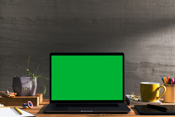 Chroma key green screen laptop on table with creative tools