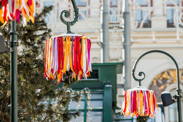 Moscow seasons. Decorations on Tverskaya Street in honor of the celebration of the traditional Russian holiday Maslenitsa. The image of the Sun and multicolored ribbons on street lamps.