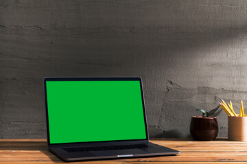 Chroma key green screen, angled view laptop on table.