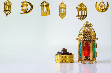 Golden lantern with dates fruit on white background with decorated lights for the Muslim feast of the holy month of Ramadan Kareem.