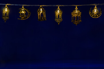 Ramadan decorated lights hanging on dark blue background for the Muslim feast of the holy month of Ramadan Kareem.