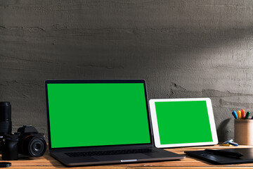 Chroma key green screen, angled view laptop and digital tablet on table with digital photography...