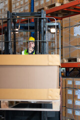 Naklejka premium Worker in auto parts warehouse use a forklift to work to bring the box of auto parts into the storage shelf of the warehouse waiting for delivery to the car assembly line