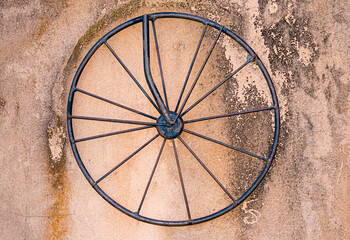 Rod iron bicycle wheel on dirty concrete wall background texture