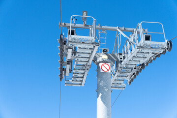 Ski chair lift over blue sky. Ski lift empty ropeway on hilghland mountain winter. Ski chairlift cable way with people enjoy skiing and snowboarding