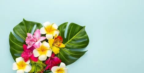 Fotobehang Spa Summer background with tropical orchid flowers and green tropical palm leaves on light background. Flat lay, top view.