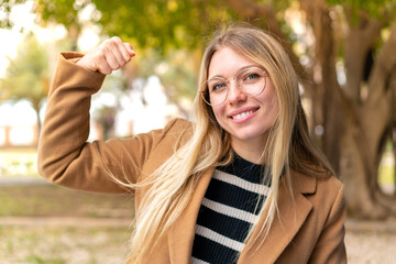 Young pretty blonde woman at outdoors doing strong gesture