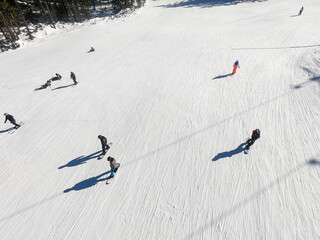 Ski resort with mountain peaks, pine trees, ski slope, restaurants and ski lifts, people skiing and...