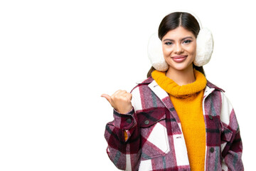Young Russian woman wearing winter muffs over isolated chroma key background pointing to the side...