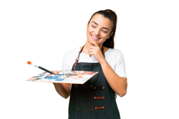 Young artist woman holding a palette over isolated chroma key background looking to the side and smiling