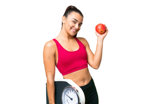 Young beauty woman over isolated chroma key background with weighing machine and with an apple