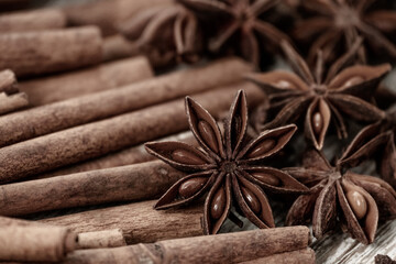 Obraz na płótnie Canvas Background with cinnamon sticks, anise stars, coffee beans and nuts. Spicy trendy background. Close-up of various spices on wooden table top view