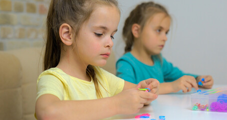 Girl weaving bracelets made of multicolored rubber bands