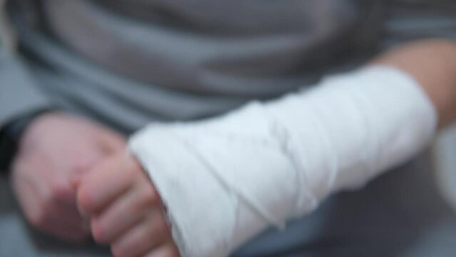 Man with plaster cast on arm. The difficulty of self-movement of the hand at a fracture. Painful heavy movements of broken finger hands close-up.