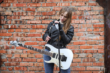  A rock musician girl in a leather jacket with a guitar