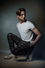 male fashion model crouch and pose deliberate in studio, showcasing his chiseled features and...