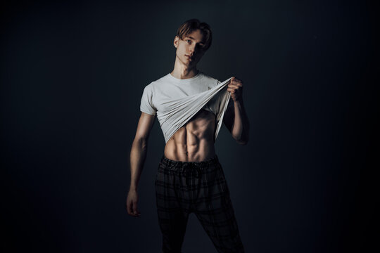 confident handsome and hot guy show flirty face expression and lift white shirt to show his sexy trained body while being satisfied and confident with Self-esteem