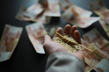 The concept of the cost of grain. 5000 ruble banknotes around a handful of ground grain. World hunger.