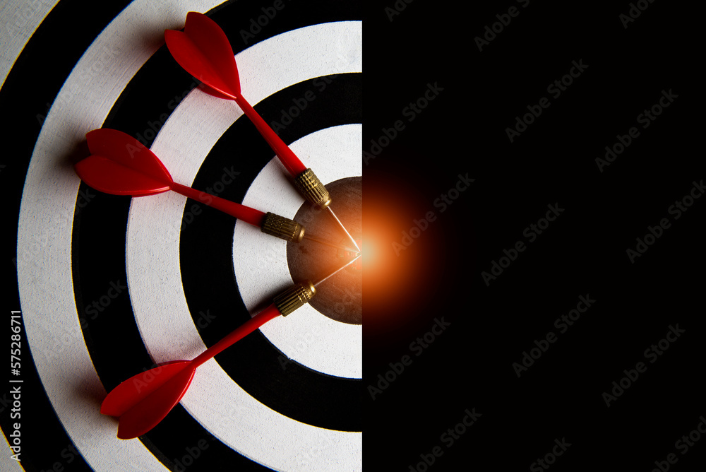 Wall mural A red dart in the middle of a target board with a black background. The concept of setting goals for business success. with copy space for text.