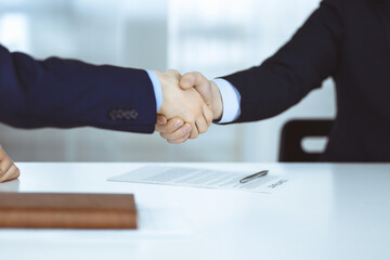 Business people shaking hands at meeting or negotiation, close-up. Group of unknown businessmen in a modern office. Teamwork, partnership and handshake concept