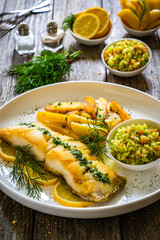 Fish dish - fried cod with French fries and cabbage salad on wooden table
