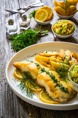 Fish dish - fried cod with French fries and cabbage salad on wooden table
